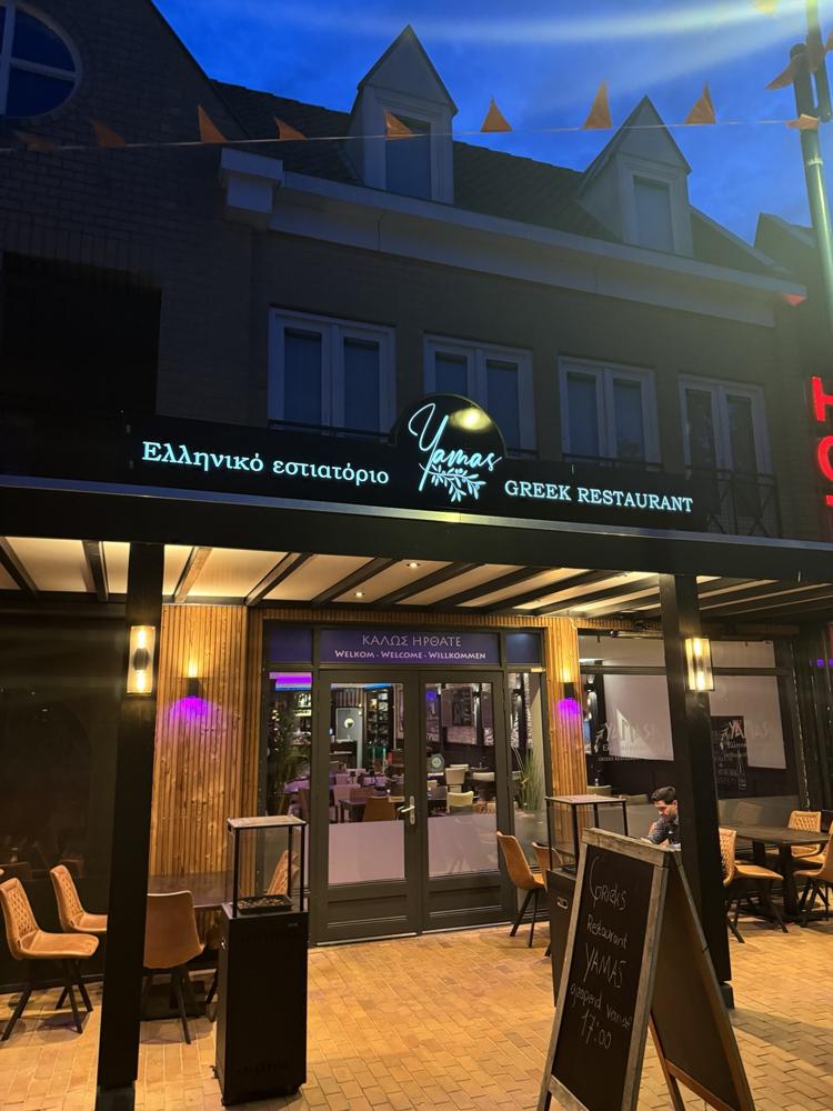 De warm verlichte entree van Yamas in de avond